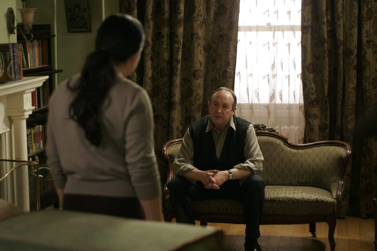 Mark Whelan seated in a parlour scene from Love and Savagery