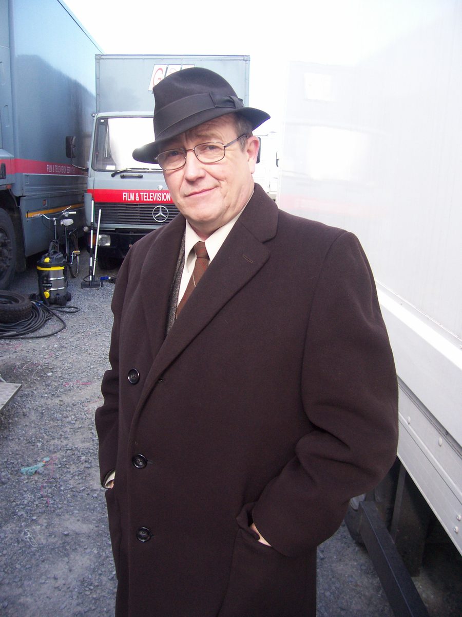 Mark Whelan in a period overcoat and fedora on location